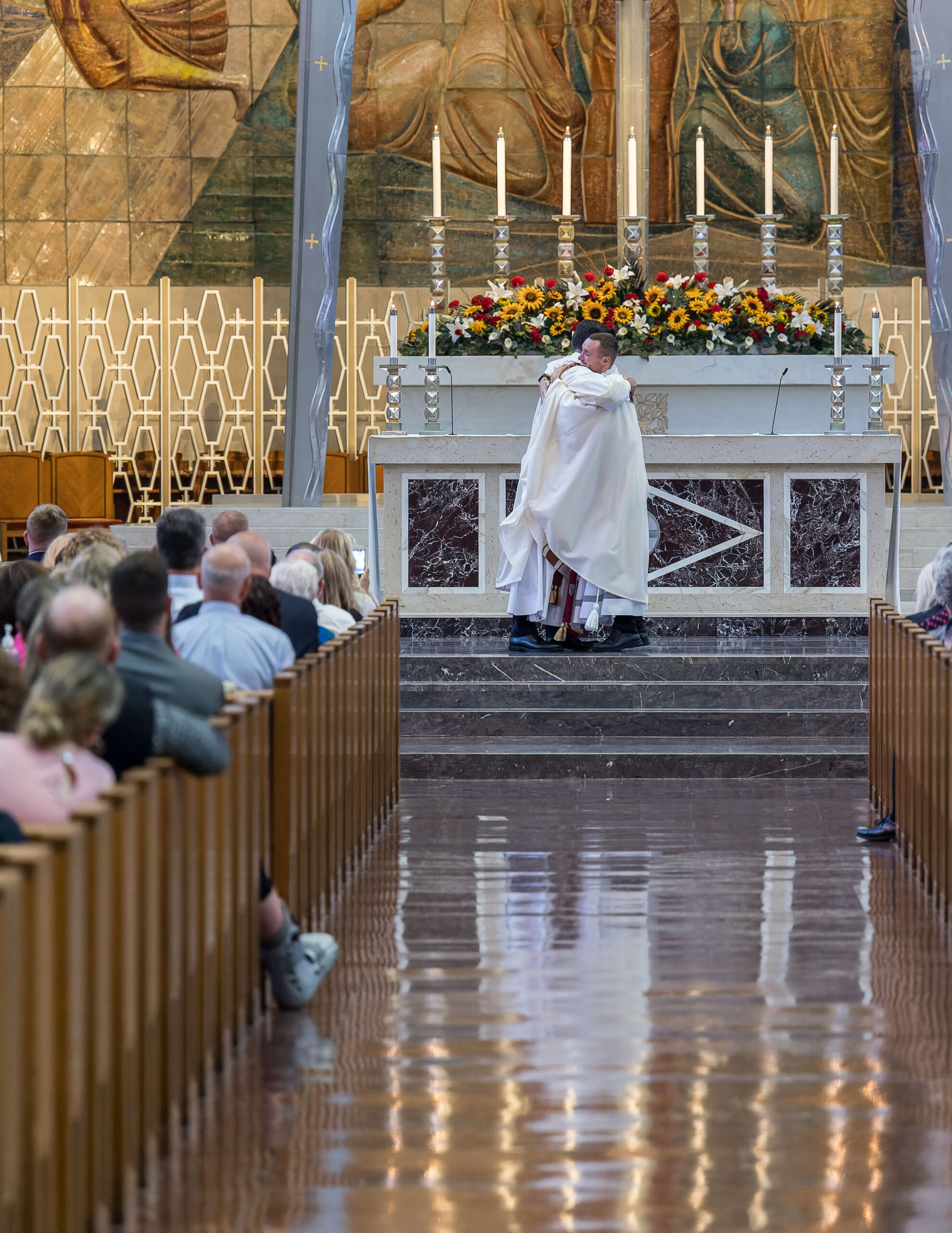 Father Joseph MacNeill, left, and Father Matthew Collins, right, embrace at the conclusion of the Kiss of Peace as they realize they are now priests. Photo by Aaron Joseph